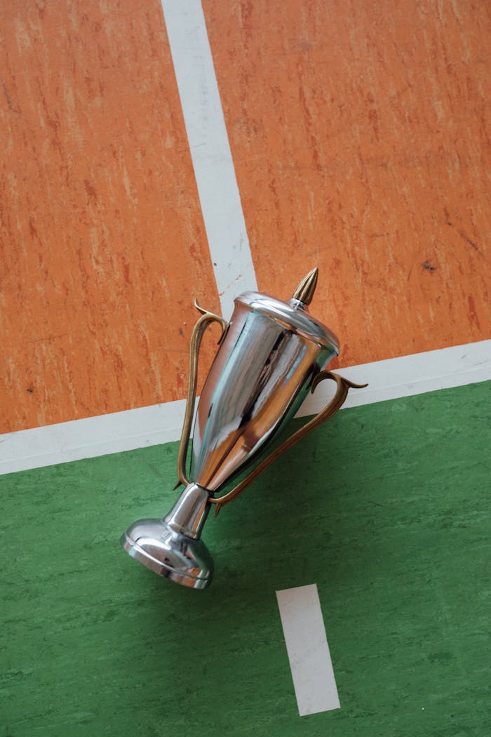 A shiny stainless steel trophy laying on a vibrant sports court surface, ready for a victor.