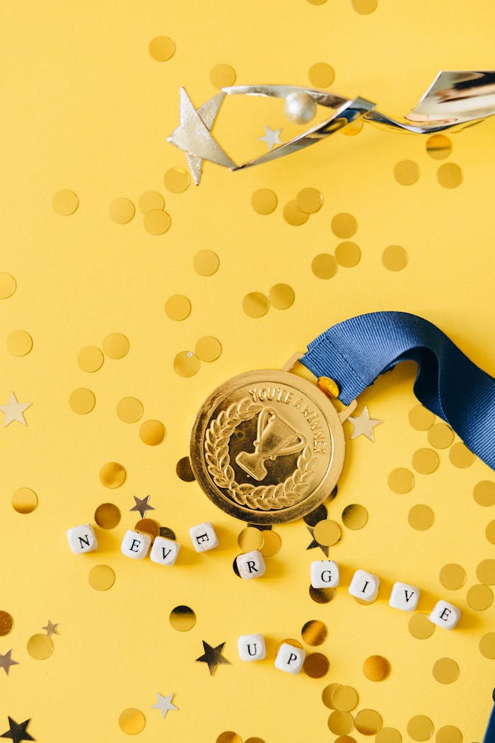 A gold medal with a blue ribbon and 'Never Give Up' message on a vibrant yellow background.